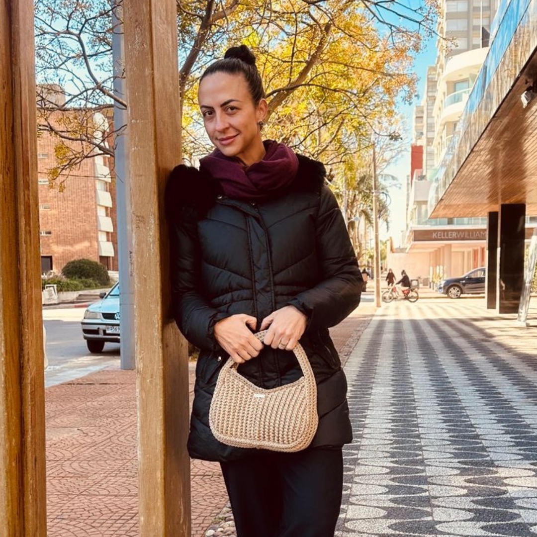 Bolsa Serena no look — modelo usando a peça em ambiente urbano com casaco preto e cachecol vinho